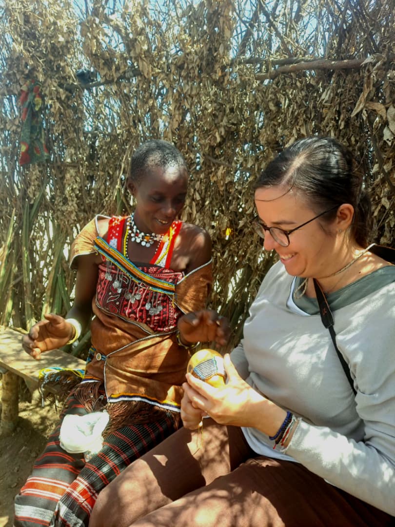 Guest learning to bead a decorated gourd with a Datoga woman in the shade