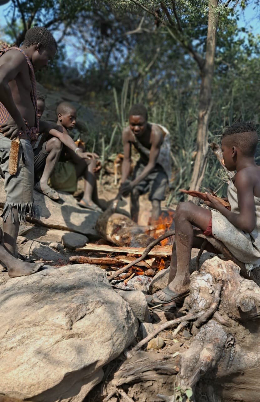 Hadzabe hunters roasting the morning's catch over an open fire on rocks