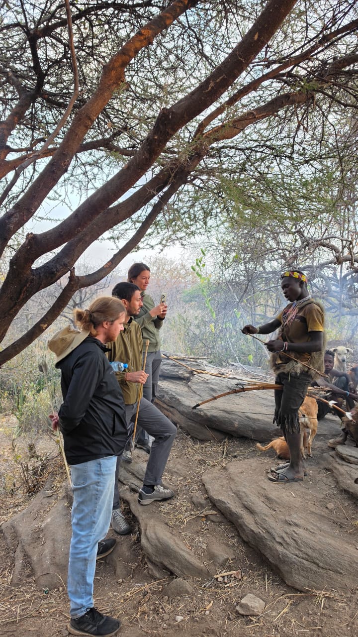 Hadzabe hunter showing guests how he fletches an arrow on the rocks