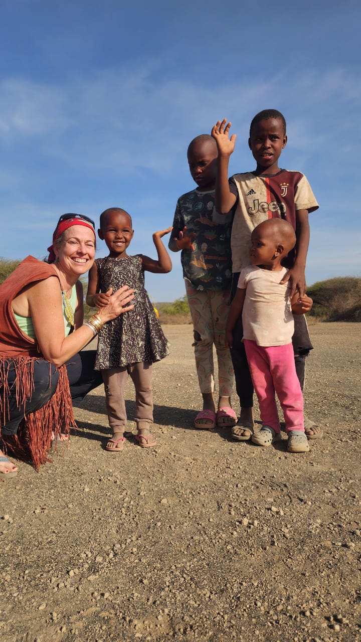 Guest crouching to greet a group of smiling village children