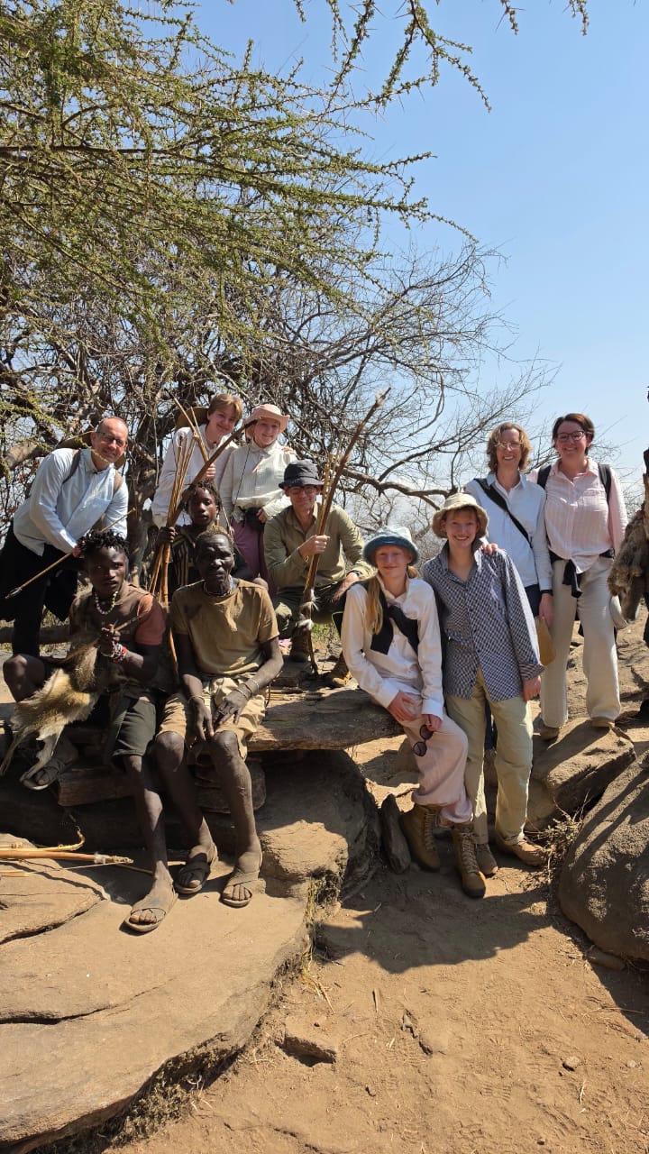 A family group of travellers with Hadzabe hunters on rocky outcrops