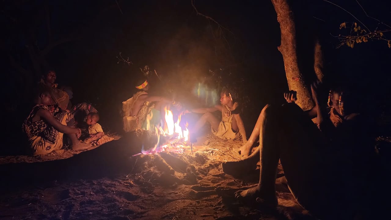 Hadzabe mothers and children seated around a fire at night