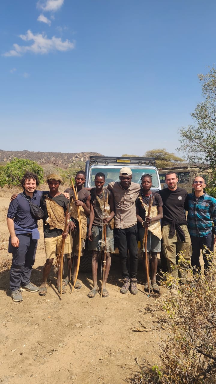 Travellers and Hadzabe hunters with bows after a morning hunt