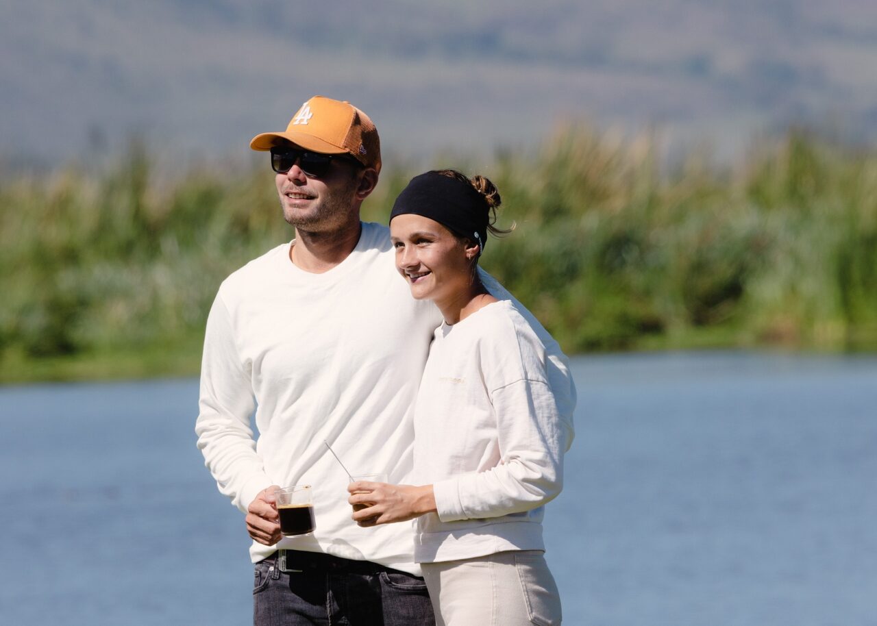 Couple smiling with coffee in hand by a Tanzanian lake